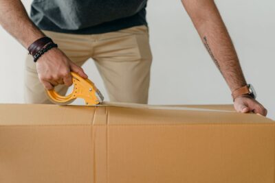 Packer using a tape gun dispenser to seal cartons