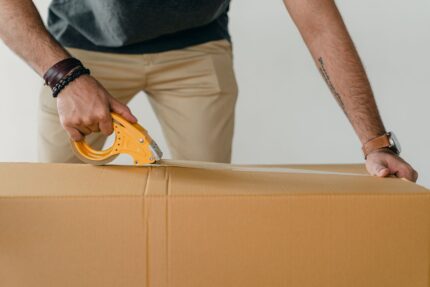 Packer using a tape gun dispenser to seal cartons
