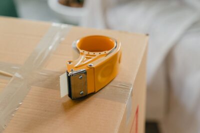 Yellow tape gun dispenser on a packed cardboard box